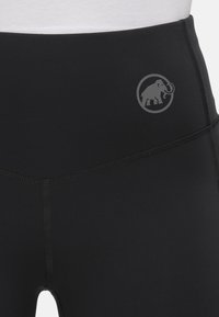 Leggings neri con vita alta, texture liscia e un logo grigio sottile che raffigura un elefante all'interno di un cerchio sul lato sinistro superiore.
