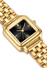 Kuldse tooni ruudukujuline käekell musta kelladialiga, minimalistlik disain, kuldsed käed ja tekstuuriga metallpael. Brändi logo on näidatud kelladialil.