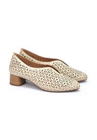 Chaussures en cuir perforé beige avec un bout rond et un petit talon en bois, présentant des découpes florales et une doublure intérieure lisse.