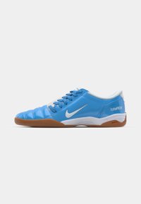 Blaue Sport Schuhe mit einem glatten synthetischen Obermaterial, weißen Akzenten und einer Gummisohle; ausgestattet mit Schnürsenkeln und einer Markenkennzeichnung an der Seite.