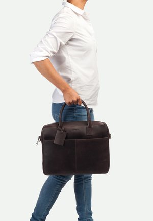 Sacoche à ordinateur en cuir marron avec un design structuré, deux poignées, une poche avant et une étiquette de bagages. Texture lisse et coutures durables.