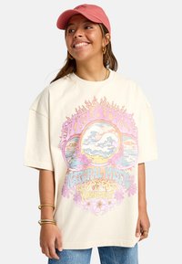 Cream oversized t-shirt featuring a colorful graphic design with waves, flowers, and text. Soft cotton material, relaxed fit.