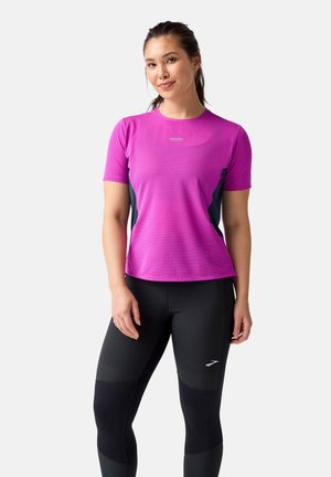 Pink short-sleeve athletic top with textured fabric, paired with black fitted leggings featuring accents and panel details.