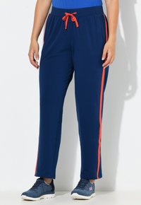 Marineblauwe joggingbroek met een elastische tailleband, oranje trekkoord en zijstrepen. Zachte stof met een losse, rechte pijp en zakken.