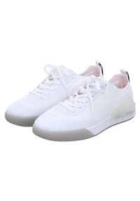 Zapatos deportivos blancos con una parte superior lisa, lengüeta acolchada y cordones. Suela exterior translúcida gris y una marca sutil en el lateral.