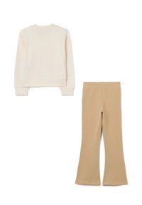 Felpa crema con polsini e orlo a coste, abbinata a leggings svasati color sabbia. Entrambi realizzati in tessuto morbido e elasticizzato.