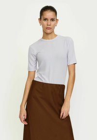 Svijetloljubičasta majica kratkih rukava s okruglim izrezom, u kombinaciji s smešnim suknjom srednje dužine, tkanina je glatka i prilagođena.