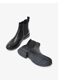 Schwarze Leder Chelsea-Stiefel mit elastischen Seitenpaneelen und Ziehschlaufe, ausgestattet mit einer strukturierten Gummisohle und einem eleganten Design.