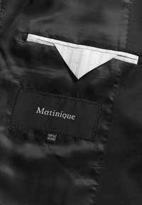 Juodos satino pamušalas striukėje, su balta kišene, turinčia plonas juosteles, ir etiketė "Matinique", siuvinėta ant audinio žymės.