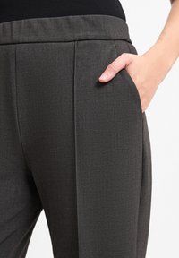 Gray structured trousers with a textured fabric, featuring a side pocket and a tapered design. The waistband is elastic for comfort.