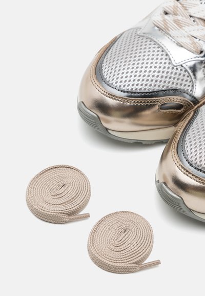 Scarpe sportive con rete argento e accenti bronzo; includono due lacci a spirale beige accanto alle scarpe.