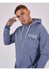 Grijs-blauwe hoodie met een voorzak en een klein logopatch. Voorzien van een capuchon met trekkoord en een textuurstof met gemanchette mouwen.