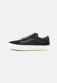 Black canvas sneakers featuring a white rubber sole, metallic decorative laces, and a side logo. Low-top design with smooth texture.