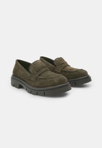 Tumedast rohelisest nahast loafers, millega on laiem rihm üle ülaosa, tukkad mustad kummitaldad ja tikitud detailid. Madala profiiliga disain mugavuse tagamiseks.