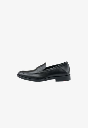 Schwarze Leder-Loafer mit schlankem Design, leicht erhöhtem Gummisohle und dekorativer Naht über dem Spann. Minimale Akzente.