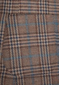 Brązowa i beżowa tkanina tkana w kratę. Zawiera niebieskie akcenty i ciemne linie, tworzące teksturowany, wielowarstwowy wygląd.