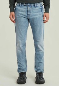 Jasnoniebieskie dżinsy o luźnym kroju, z subtelnym przetarciem, przednimi kieszeniami i przeszyciami wzdłuż szwów.