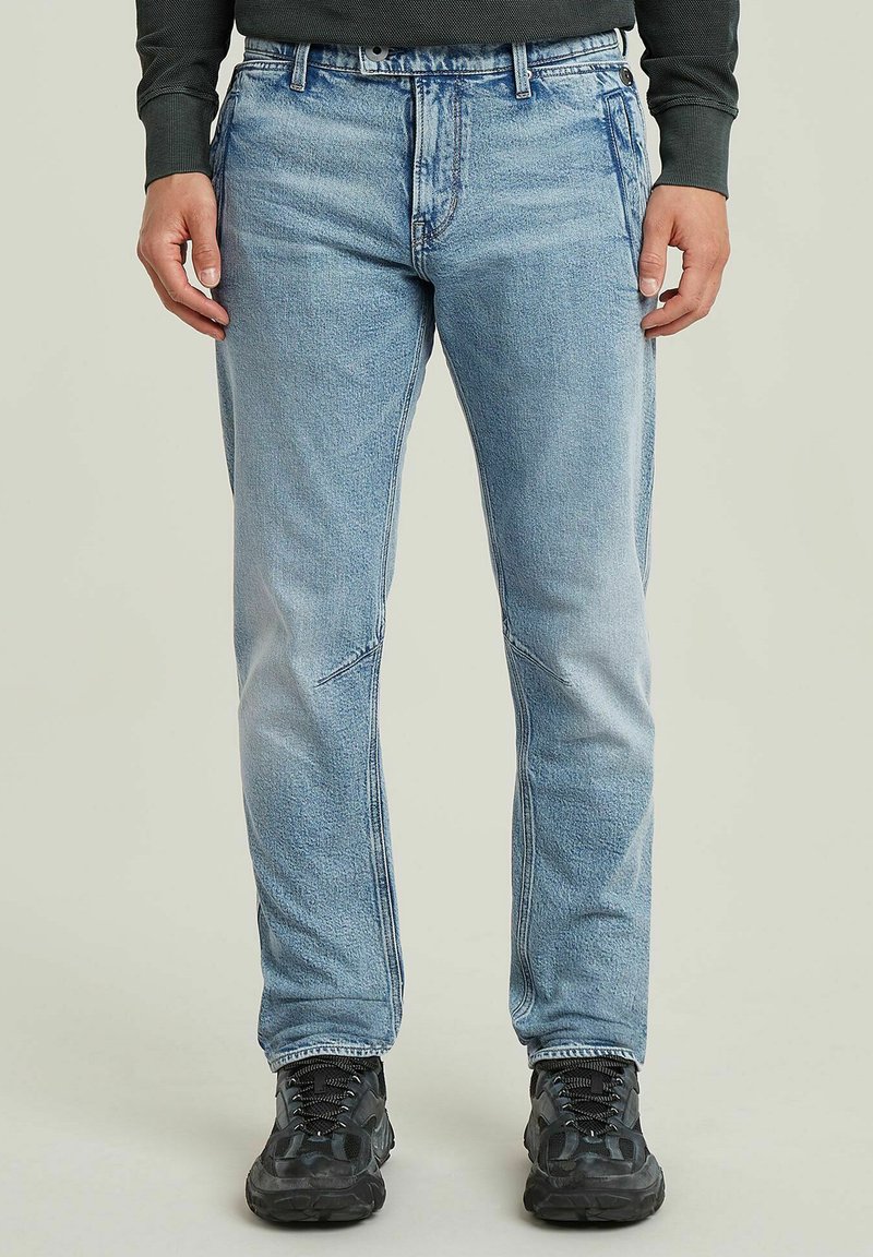 Jasnoniebieskie dżinsy o luźnym kroju, z subtelnym przetarciem, przednimi kieszeniami i przeszyciami wzdłuż szwów.