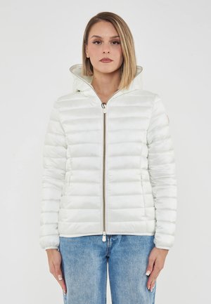 Giubbotto imbottito bianco con cappuccio e texture trapuntata. Presenta una chiusura frontale con zip e polsini a coste. Abbinato a jeans azzurri chiari.