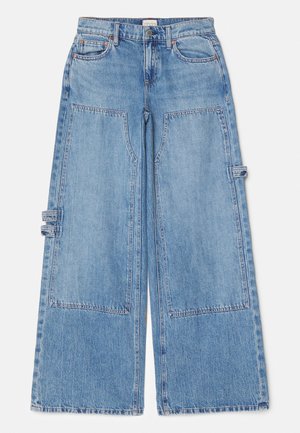 Vaaleansiniset väljät farkut suurilla etutaskuilla. Valmistettu denimmateriaalista, jossa on nappikiinnitys, vyölenkit ja hienovaraiset tikkausviivat.
