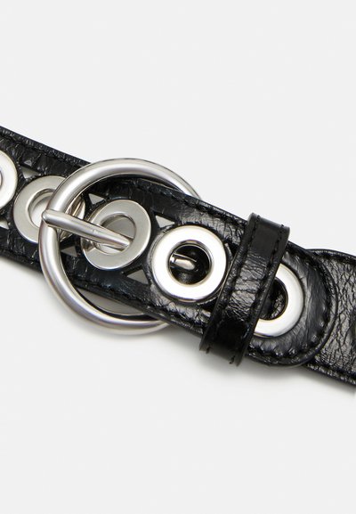 Svart läderbälte med silverfärgad metalldetaljer, med cirkulära urtag och en stor ringspänne, texturerad yta och sydda kanter.