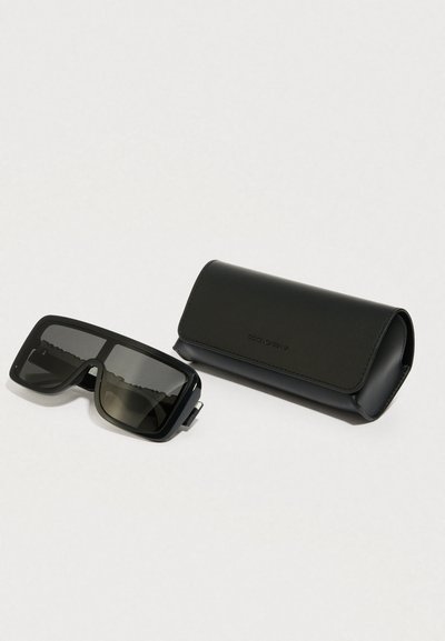 Mustad ristkülikukujulised päikeseprillid tumedate läätsedega koos sobiva musta nahkkotiga. Kott on sileda tekstuuriga ja tal on volditav kaas.