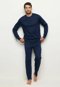 Sininen pitkähihaisen puseron ja vastaavien housujen yhdistelmä, valmistettu pehmeästä kankaasta. Puserossa on pyöreä kaula-aukko ja rento istuvuus, jossa on yksinkertainen muotoilu.