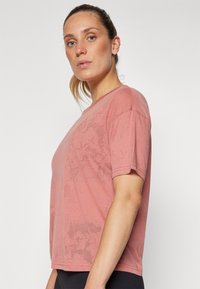 Short-sleeve, relaxed-fit t-shirt in a dusty pink hue, crafted from lightweight fabric with a subtle texture and minimal design.