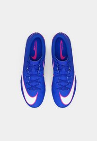 Μπλε ποδοσφαιρικά παπούτσια Nike Mercurial με μαλακή υφή, φωτεινές ροζ λεπτομέρειες και μια προεξέχουσα λευκή σχεδίαση σούσι, διαθέτουν κλείσιμο με κορδόνια.