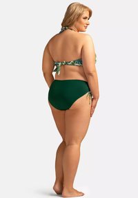 Zestaw bikini składający się z topu w zielono-białe wzory z wiązaniem z tyłu, uzupełnionego jednolitymi, zielonymi majtkami o wysokim stanie z bocznymi wiązaniami.
