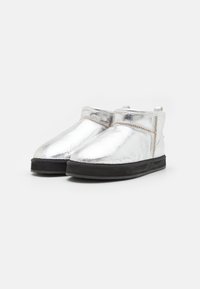 Botine metalice argintii, cu o textură netedă, tălpi din cauciuc negre și un design simplu. Au un tab pentru a fi îmbrăcate ușor.