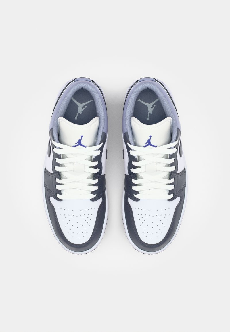 Sneaker bianca e navy con tomaia in pelle, punta perforata e lacci. Presenta il logo iconico vicino al tallone e sulla linguetta.