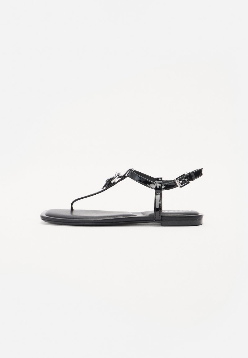 Sandálias de verniz preto com um design minimalista, apresentando uma tira para os dedos, fivela ajustável no tornozelo e sola plana.