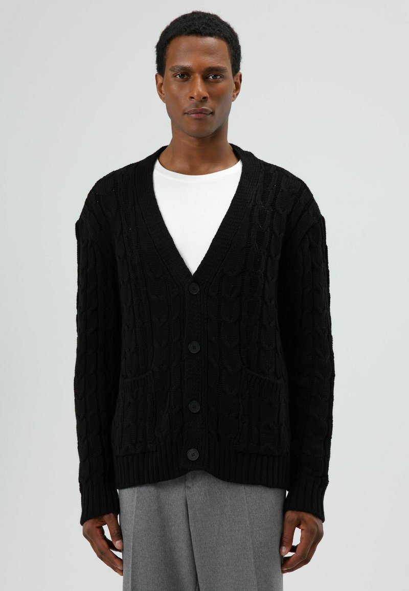 Zwarte kabelgebreide cardigan met een V-hals, vijf knopen en voorzakken. Heeft geribbelde manchetten en zoom, gemaakt van getextureerd breimateriaal.