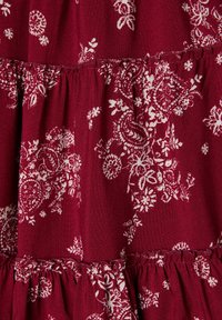 Tessuto color bordeaux con un motivo floreale bianco, con cuciture arricciate e un design fluido. Tessuto morbido e leggero, adatto per capi di abbigliamento.