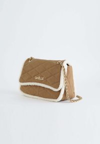 Sac à main matelassé marron avec garniture en fourrure crème, chaîne dorée et fermeture à rabat. Présente le logo de la marque à l'avant.