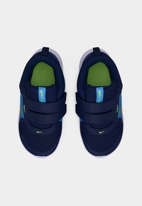 Παιδικά αθλητικά παπούτσια Nike σε μπλε ναυτικό και ανοιχτό μπλε χρώμα με πράσινες εσωτερικές σόλες, δύο λουράκια με βέλκρο και λευκές σόλες, από ψηλά σε λευκό φόντο.