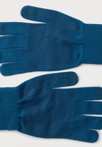 Kék, kötött kesztyűpár texturált tapadási mintákkal a tenyéren, egy világos felületen laposan elhelyezve.