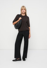 Brown short-sleeve sweater, black wide-leg pants, and black bag. Footwear is black with laces. Simple design, smooth textures, neutral colors.