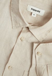Beige linnen shirt met een klassieke kraag, voorzien van parelknopen en een borstzak. Zachte textuur en lichtgewicht ontwerp. Maat M.
