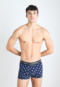 Tengerészkék boxer alsó, ismétlődő fehér grafikus ikonokkal, fekete márkás derékrésszel. Puha anyag, szoros illeszkedés.