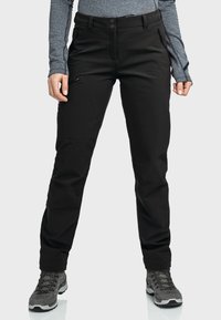 Czarne spodnie outdoorowe o slim fit, wykonane z lekkiego materiału. Posiadają kieszenie na zamek oraz subtelne detale wykończenia. Połączone z szarymi butami trekkingowymi.