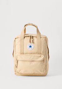 Beige tyg ryggsäck med rektangulär form, dubbla handtag upptill, ficka med dragkedja fram och en rund Converse All Star-logotyp.