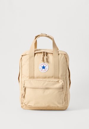 Bežinė audinio kuprinė su stačiakampio forma, dviem viršutiniais rankenomis, priekinė zip kišenė ir apvalus "Converse All Star" logotipas.