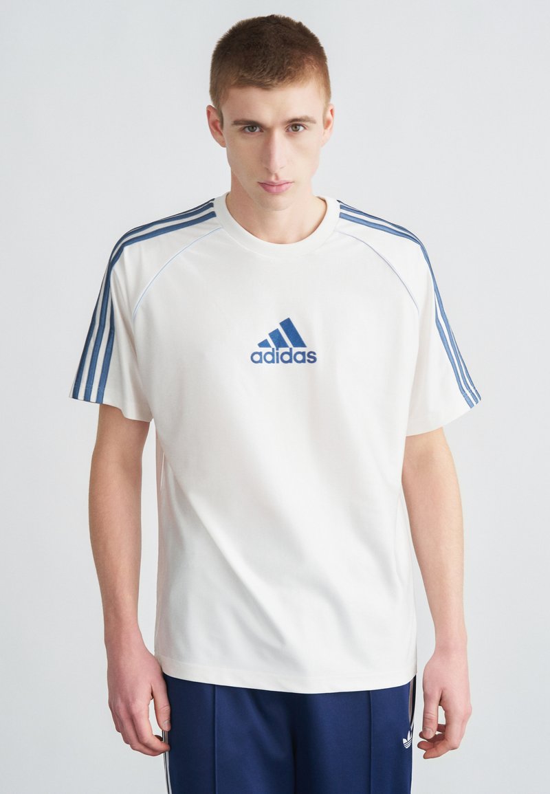 Biele športové tričko s krátkymi rukávmi, modré logo Adidas a tri modré pruhy na každom ramene, s okrúhlym výstrihom.