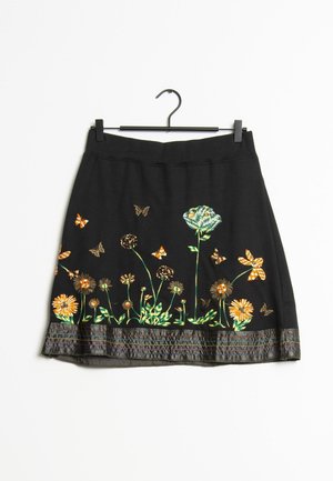 Zwarte rok met geborduurde oranje en groene bloemen en vlinders langs de zoom, hangend aan een zwarte hanger.