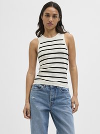 Top senza maniche a righe in crema e nero, con un design aderente. Indossato con jeans a vita alta di un blu chiaro strappati.