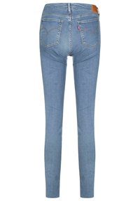 Jeans de corte ajustado hechos de denim azul claro. Presentan una cintura de altura media, diseño de cinco bolsillos y bolsillos traseros con detalles de costura curvados.