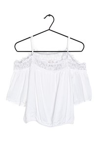White off-the-shoulder blouse with lace detailing at the neckline, short billowy sleeves, and an elastic hem. Hangs on a black hanger.