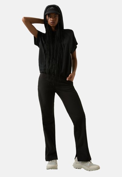 Black cropped hoodie with a hood, paired with fitted black pants and light-colored sporty shoes, showcased against a neutral background.